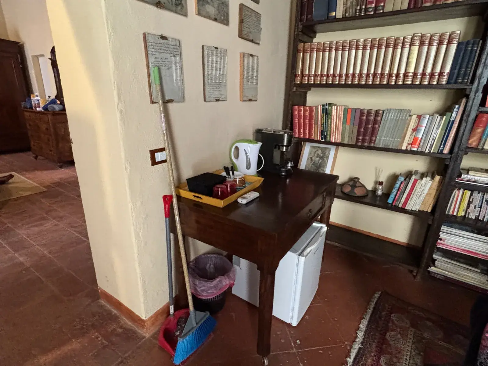 Angolo caffè e libreria delle Antiche Dimore del Vescovado con macchina del caffè, bollitore e libreria di volumi rilegati riordinati e spolverati.